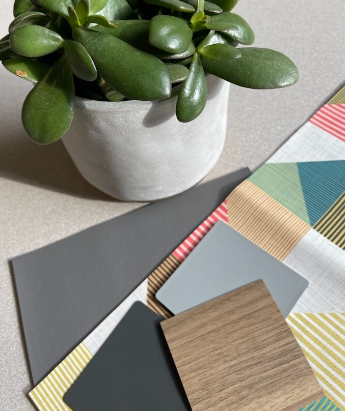 Fabric and surface swatches on grey table with succulent in background.