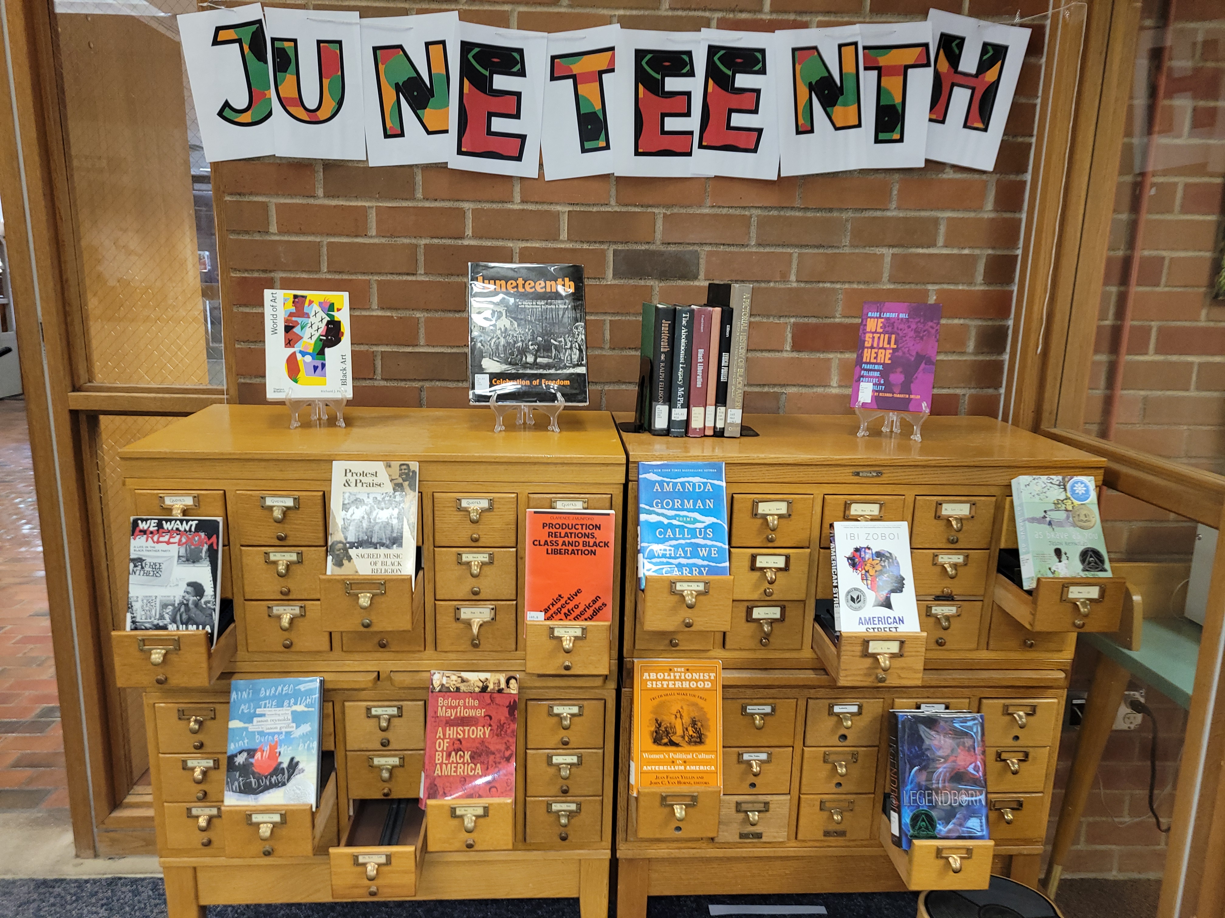 Juneteenth book display with colorful sign on brick wall